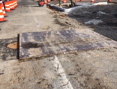 road plant in use at construction site near orange traffic cones