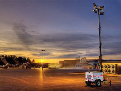 tall light plant in use at an empty lot at dusk