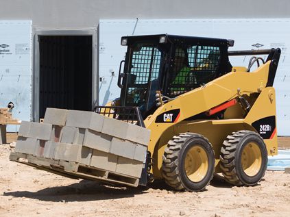 CAT skid steer hauling cement blocks at construction site