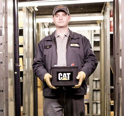 A Carter Cat employee holding a Cat battery