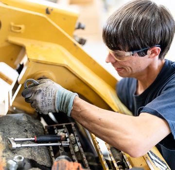 A Carter Cat employee servicing a piece of heavy machinery