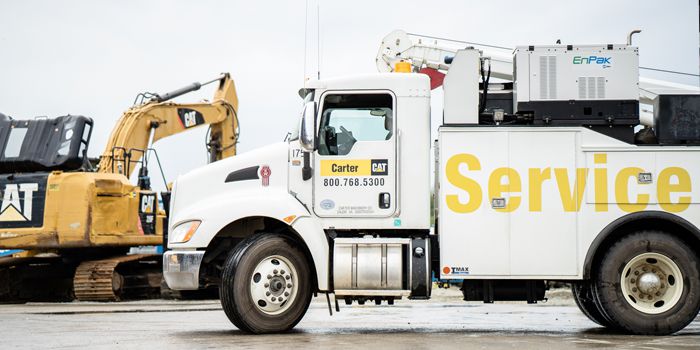 A white Carter Cat service truck and a Cat Excavator