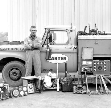 A vintage black and white photo of a Carter Cat employee in front of a Carter Cat truck