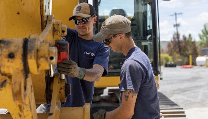 Two Carter Cat employees servicing a piece of heavy machinery