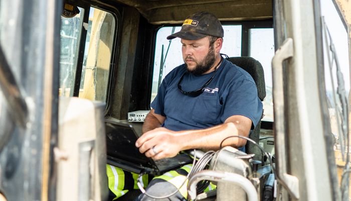 A Carter Cat employee sitting inside a Cat machine working on a laptop