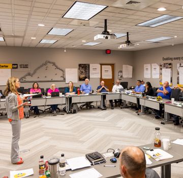 A Carter Cat employee standing up in front of other Carter Cat employees who are seated around her listening to her speak