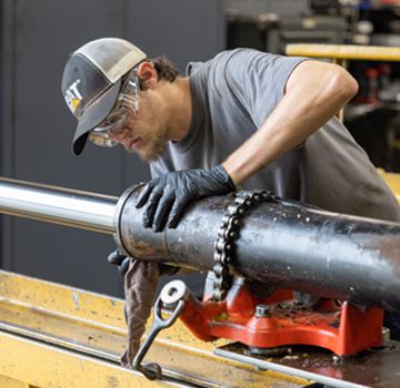 A Carter Cat employee working on a hydraulic cylinder