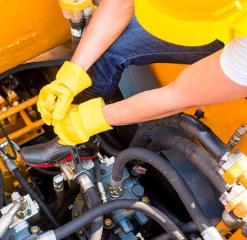 A person with yellow gloved on working on a piece of machinery