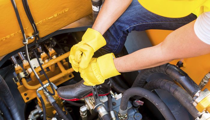 A person with yellow gloved on working on a piece of machinery