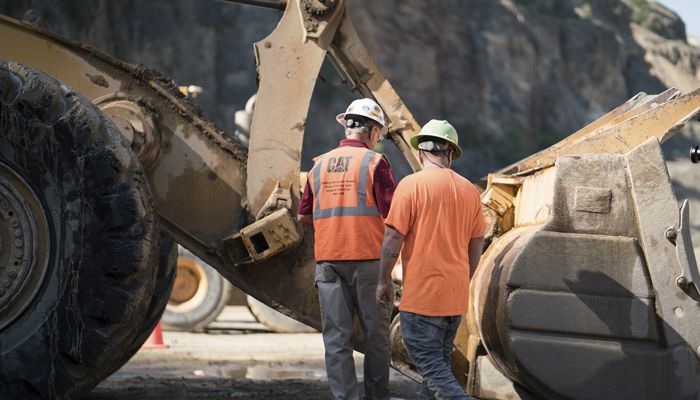 Two Carter Cat employees working on a machine out in the field