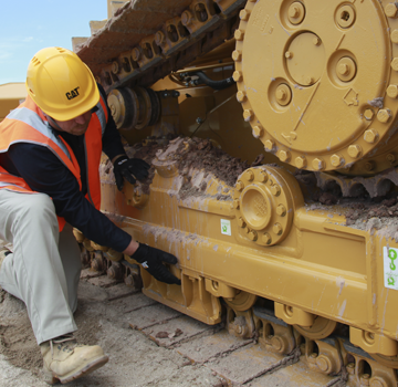 A Carter Cat employee working on a piece of heavy machinery