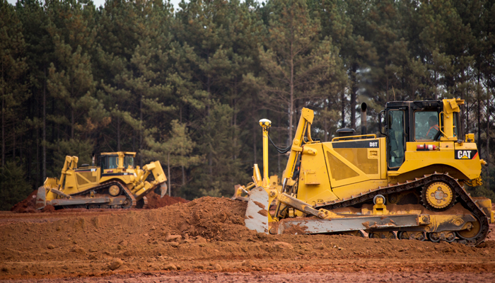 Two Cat machines at work in a field of dirt