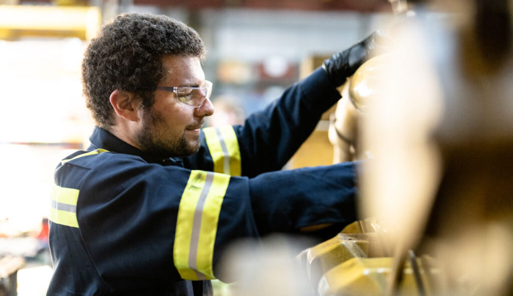 A male Carter Cat employee working on a piece of heavy machinery