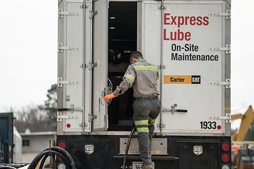 A male employee stepping in the back of Carter Cat truck