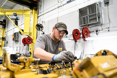 A male Carter Cat shop technician working on a piece of heavy equipment