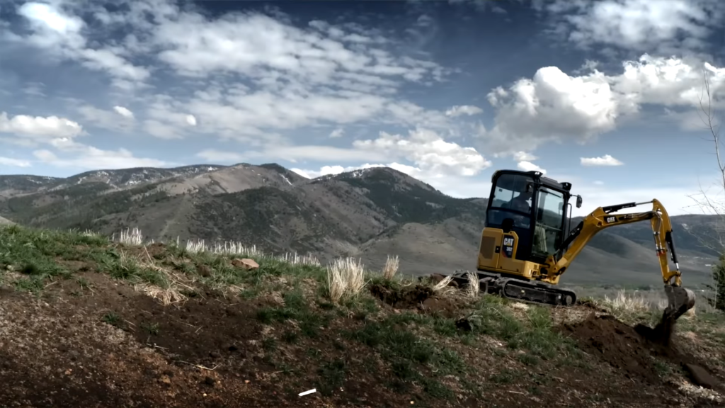 Cat mini excavator in action lifting dirt